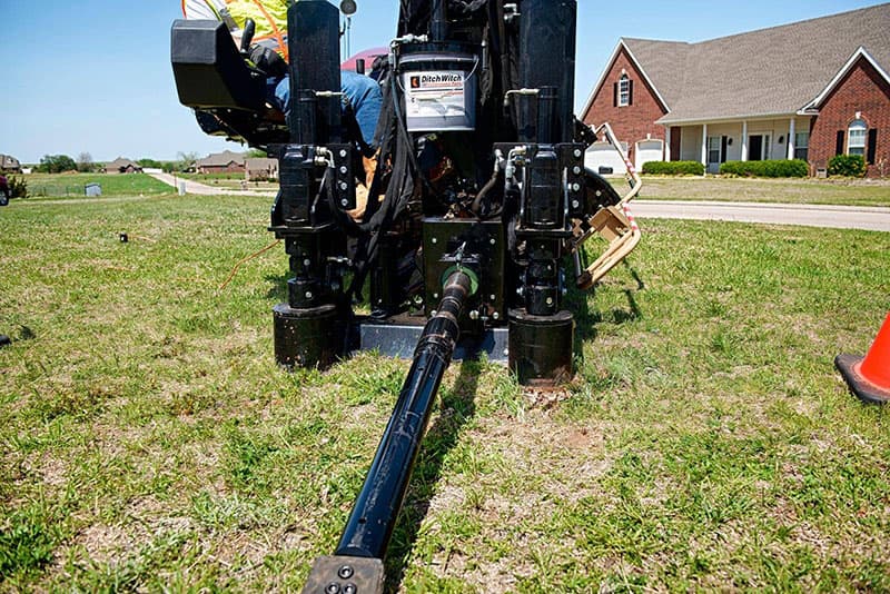 Directional drill rig with drill pipe entering the ground for a trenchless utility bore